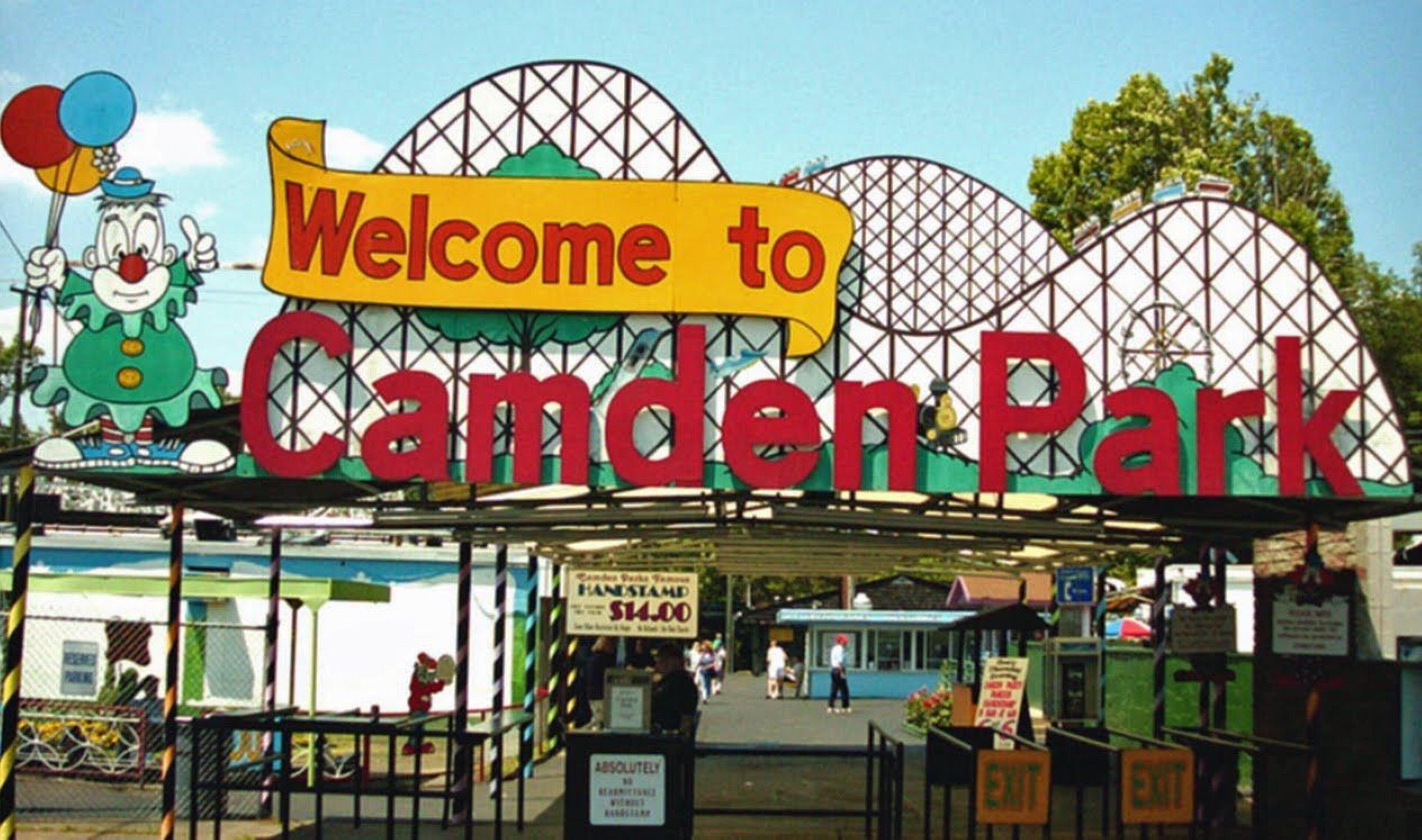 Señal de bienvenida a Camden Park, con una noria al fondo.