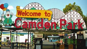 Señal de bienvenida a Camden Park, con una noria al fondo.