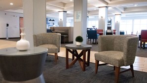 A lobby area with seating arrangements, a small table with a vase, and a sign indicating room locations. - Holiday Inn Express & Suites Ironton by IHG (Ironton)