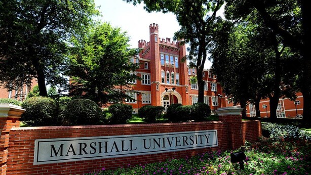 A brick building with a sign reading "MARSHALL UNIVERSITY" surrounded by lush greenery and flowers. - Holiday Inn Express & Suites Ironton by IHG (Ironton)