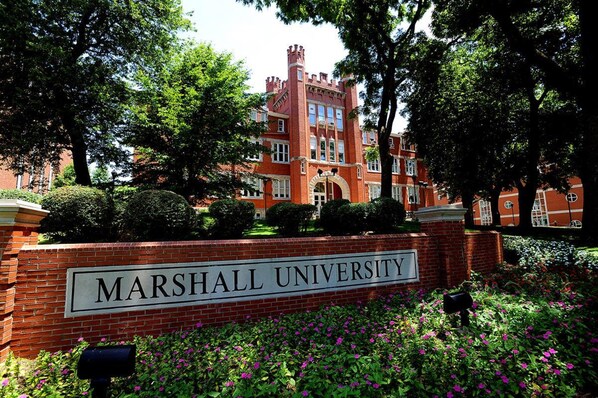 A brick building with a sign reading "MARSHALL UNIVERSITY" surrounded by lush greenery and flowers. - Holiday Inn Express & Suites Ironton by IHG (Ironton)