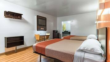 A hotel room with two beds, a desk, a television, and a mirror.