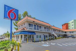 Un motel con fachada azul y blanca, techo rojo y estacionamiento con espacios reservados para discapacitados.
