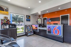 A hotel reception area with a digital kiosk, a coffee machine, and a sign advertising a 6-star rating. - Motel 6 National City Ca (National City)