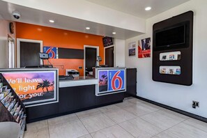 A hotel reception desk with a digital screen, a number '6' sign, and a 'motel' sign. - Motel 6 National City Ca (National City)
