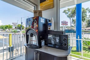 A coffee machine with a milk frother and a coffee maker, located at a gas station with a blue pillar and a CVS pharmacy sign in the background. - Motel 6 National City Ca (National City)