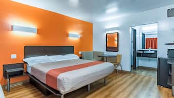 A hotel room with a bed, bedside tables, a desk, a chair, a mirror, and a bathroom.