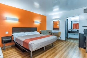 A hotel room with a bed, bedside tables, a desk, a chair, a mirror, and a bathroom. - Motel 6 National City Ca (National City)