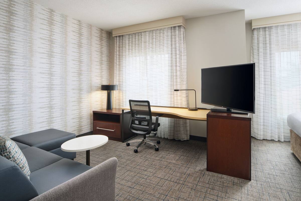 Une chambre d’hôtel équipée d’un bureau, d’une télévision, d’un canapé et d’une petite table.