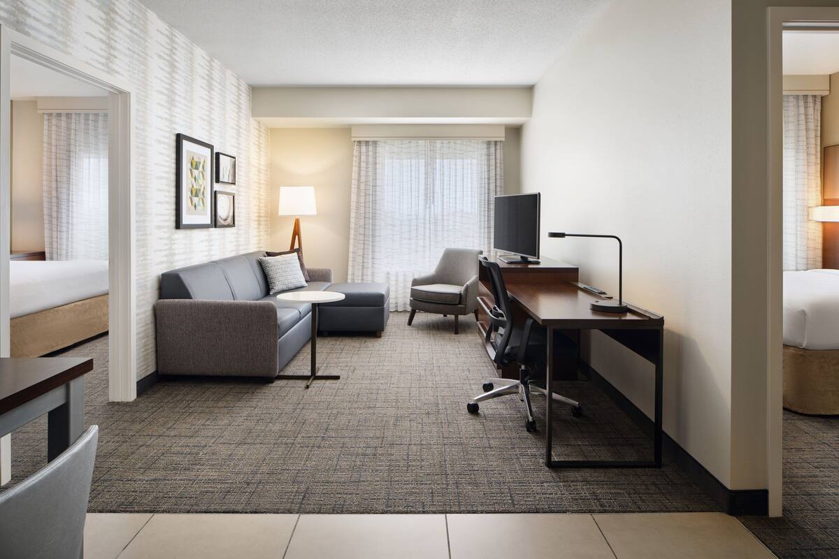 Une chambre d’hôtel équipée d’un canapé, d’un fauteuil, d’un bureau et d’une télévision.