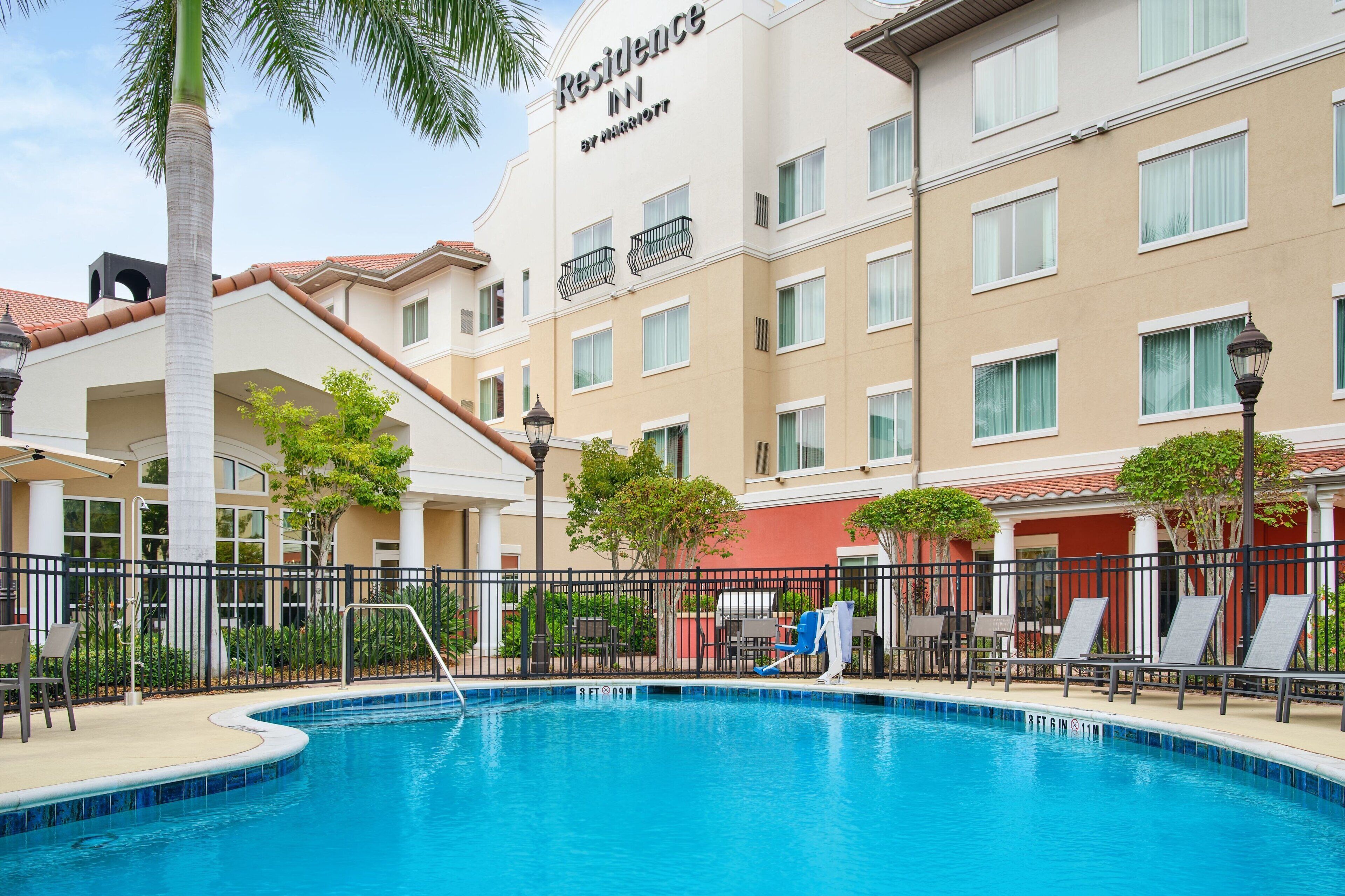 Un hotel con piscina, area relax all'aperto e una palma.
