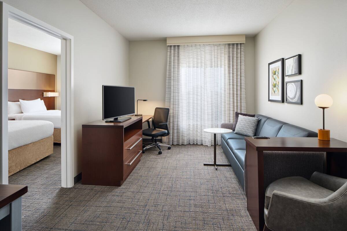 Une chambre d’hôtel comprenant un lit, un bureau avec une télévision, une chaise, un canapé et une lampe.