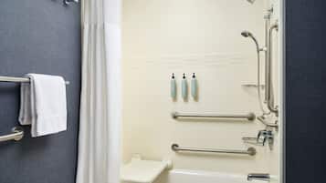 A bathroom with a bathtub, shower, and toilet. There are grab bars and a towel rack.