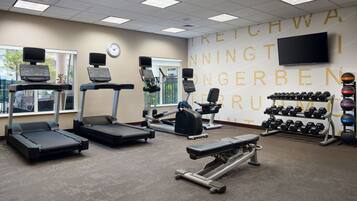 A gym with treadmills, an elliptical, a bench press, and a rack of dumbbells.