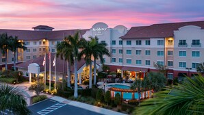 A hotel with multiple buildings, a swimming pool, and palm trees.