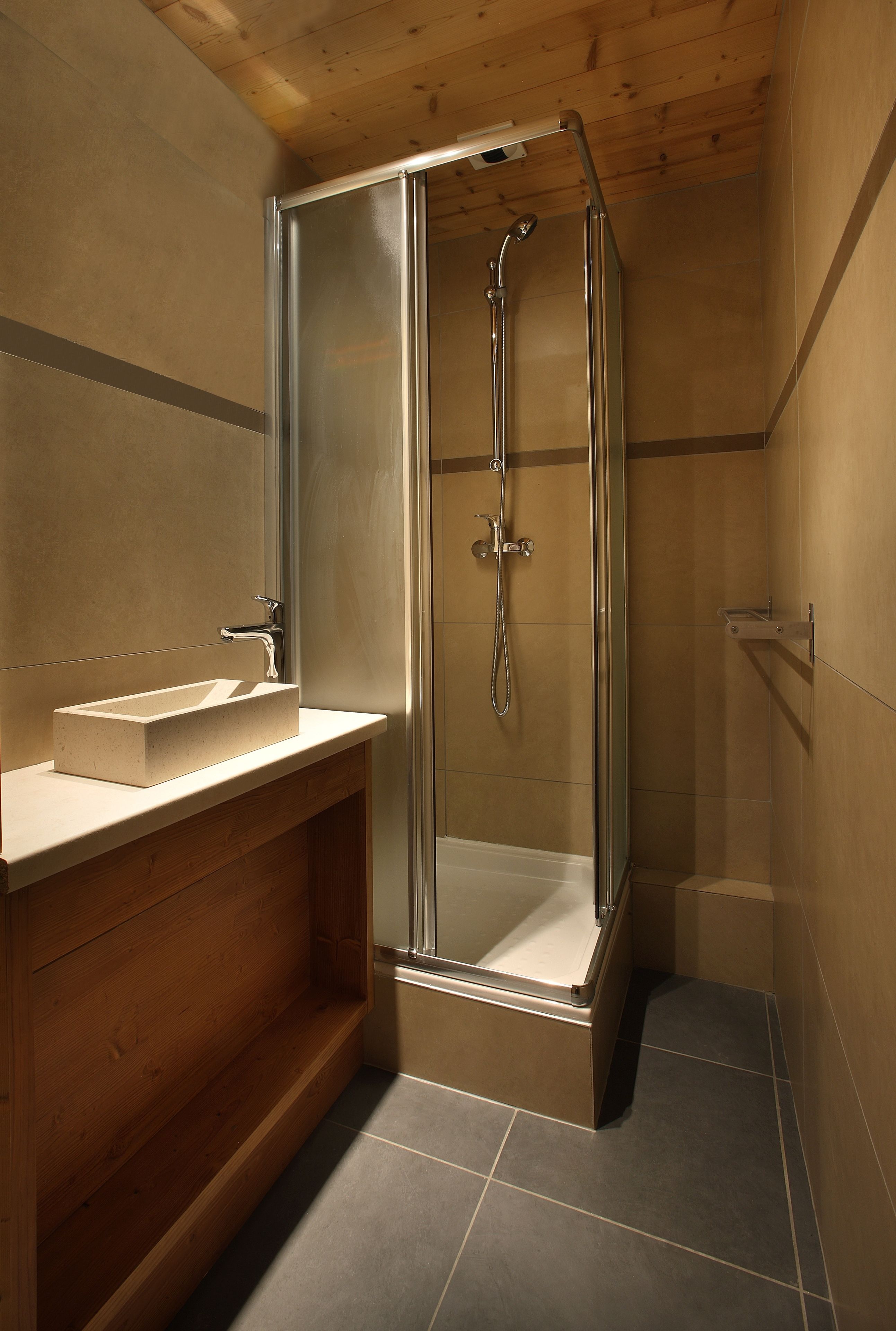 A modern bathroom with a glass-enclosed shower, a wooden vanity, and a built-in sink.
