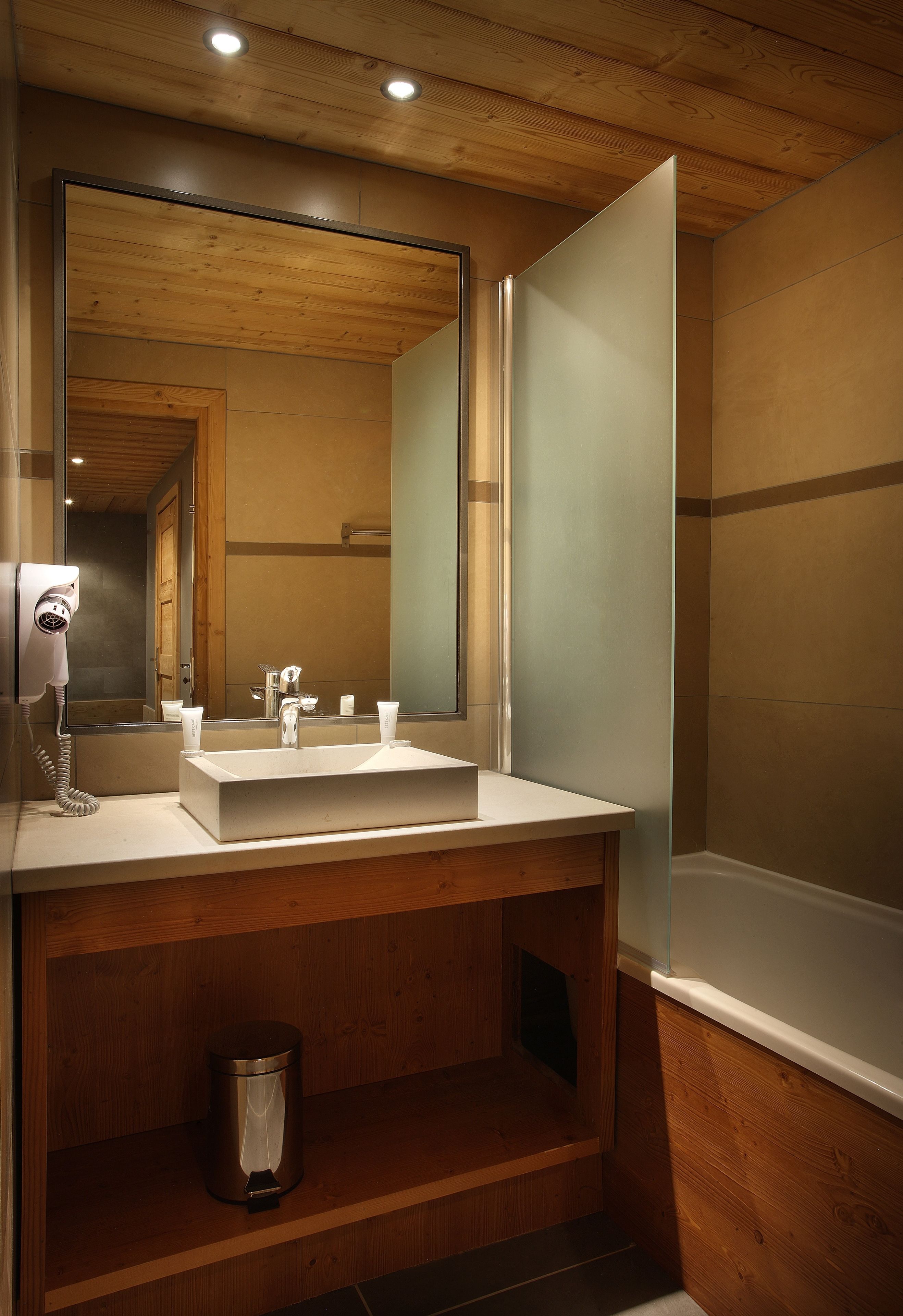 A bathroom with a wooden vanity, a large mirror, a sink, and a hairdryer.