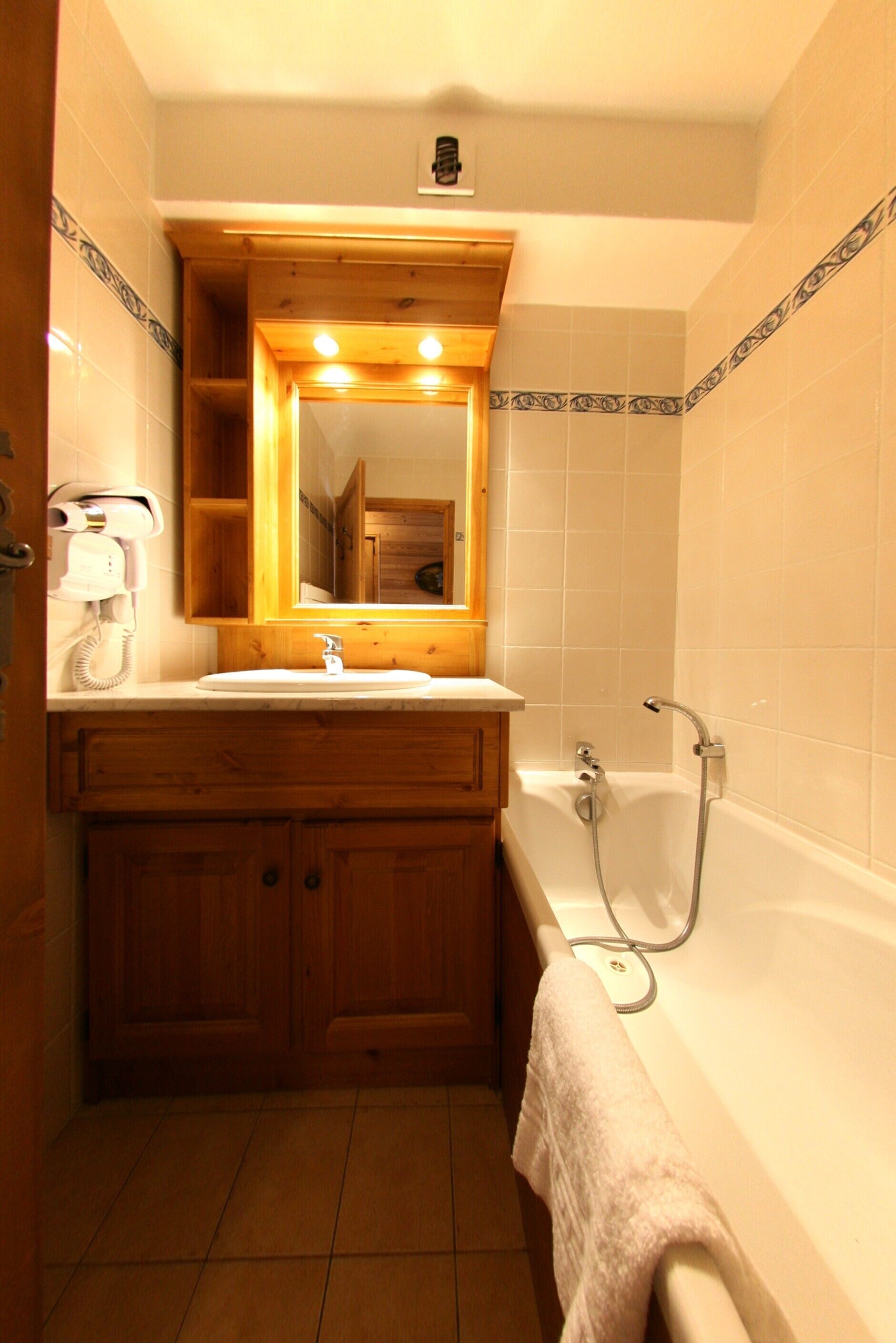 A bathroom with a wooden vanity, a sink, a mirror, a bathtub, and a towel rack.
