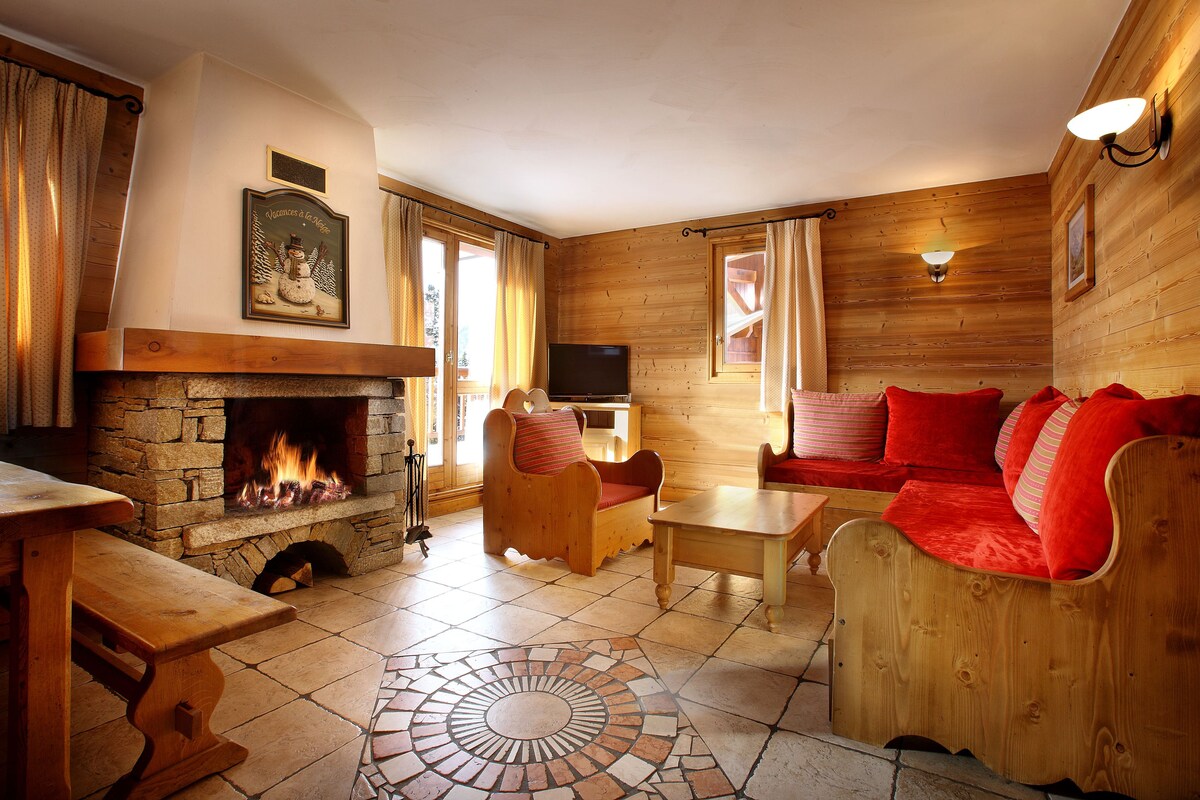 Ein gemütliches Zimmer mit Kamin aus Stein, Holzmöbeln und einem Fernseher.