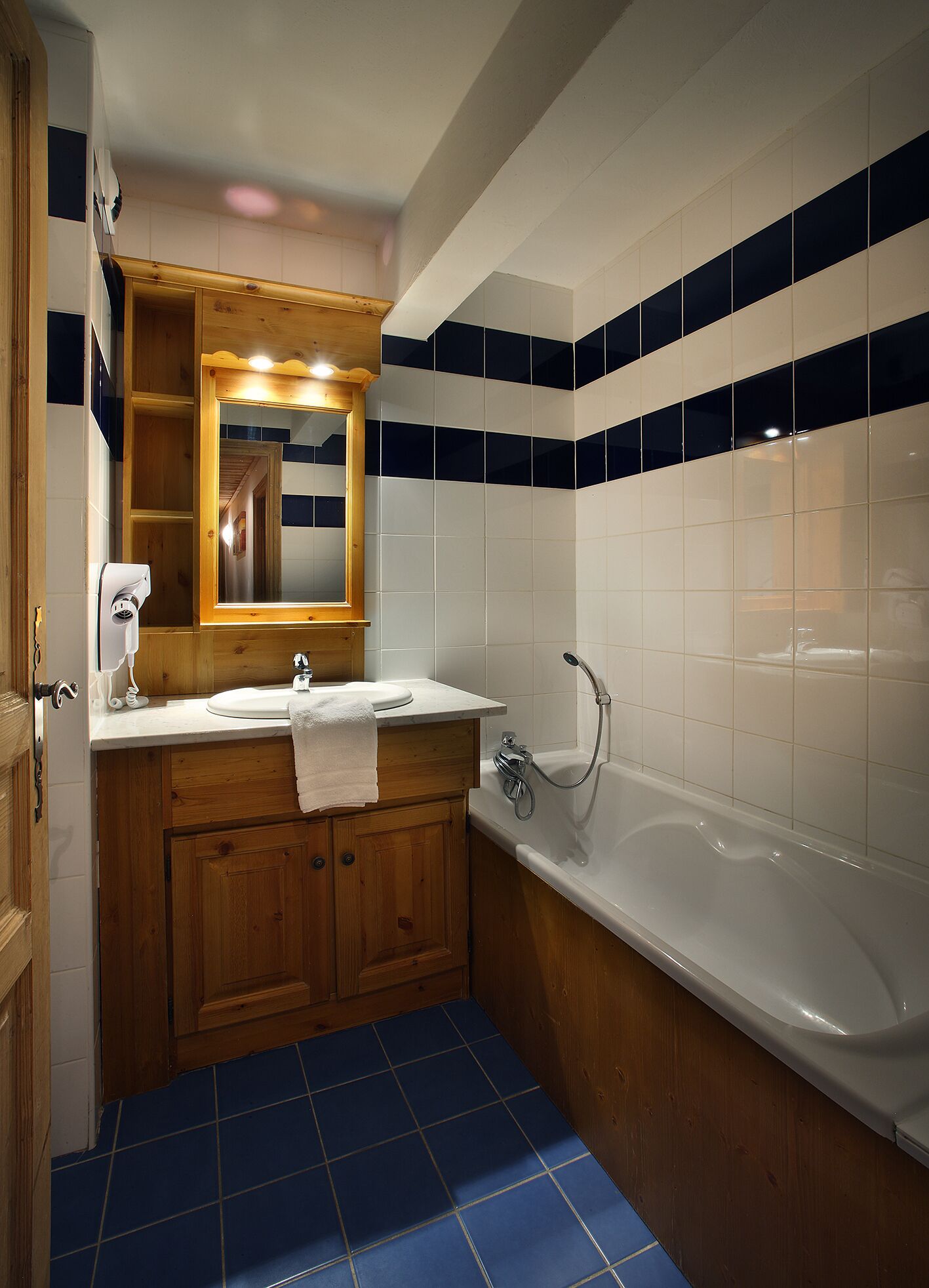 Une salle de bain avec un meuble-lavabo en bois, un lavabo blanc, un miroir et une baignoire.