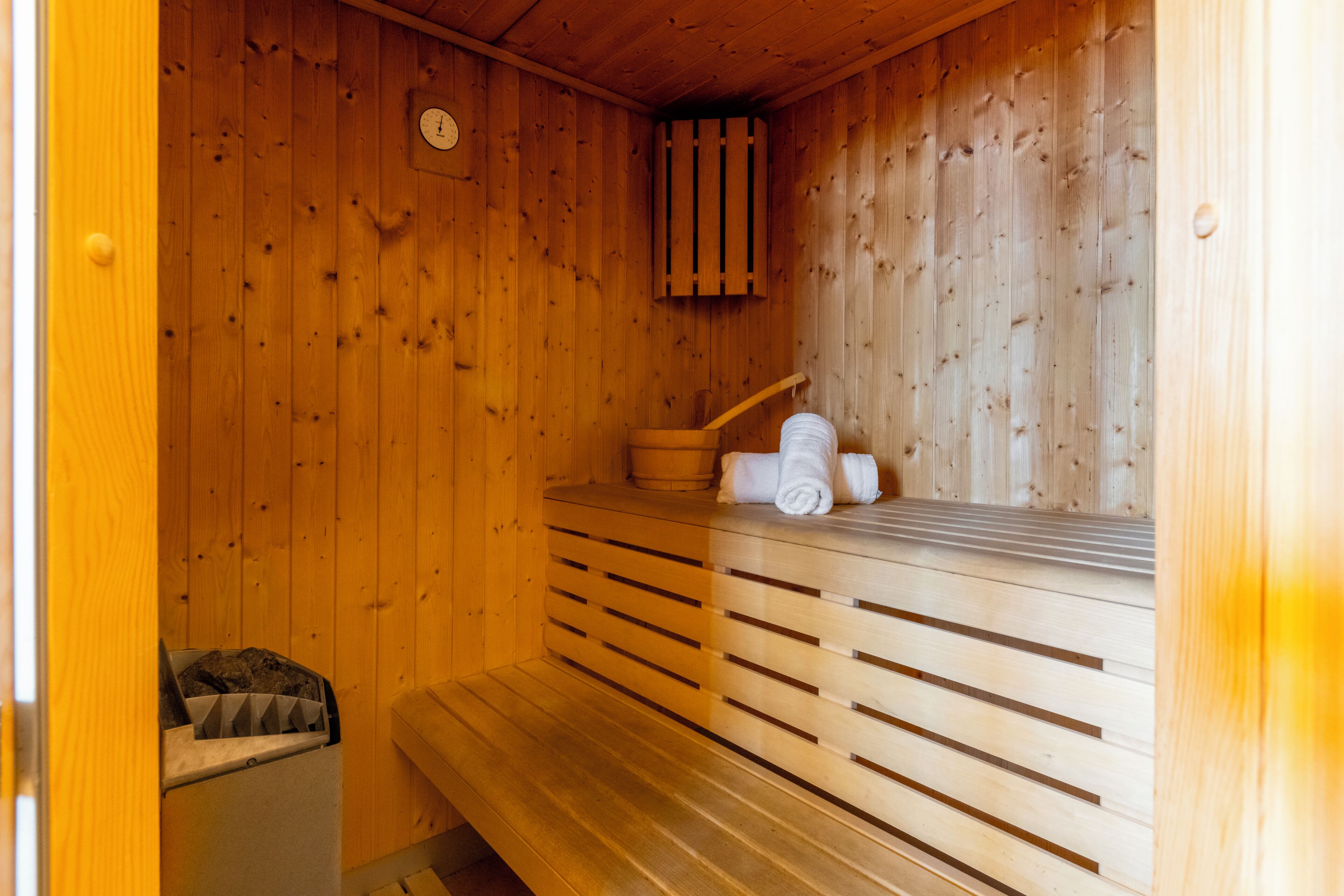 Un sauna en bois avec des bancs, un porte-serviettes et un panneau mural en bois.
