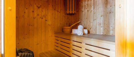 Una sauna de madera con bancos, un perchero para toallas y un panel de pared de madera.