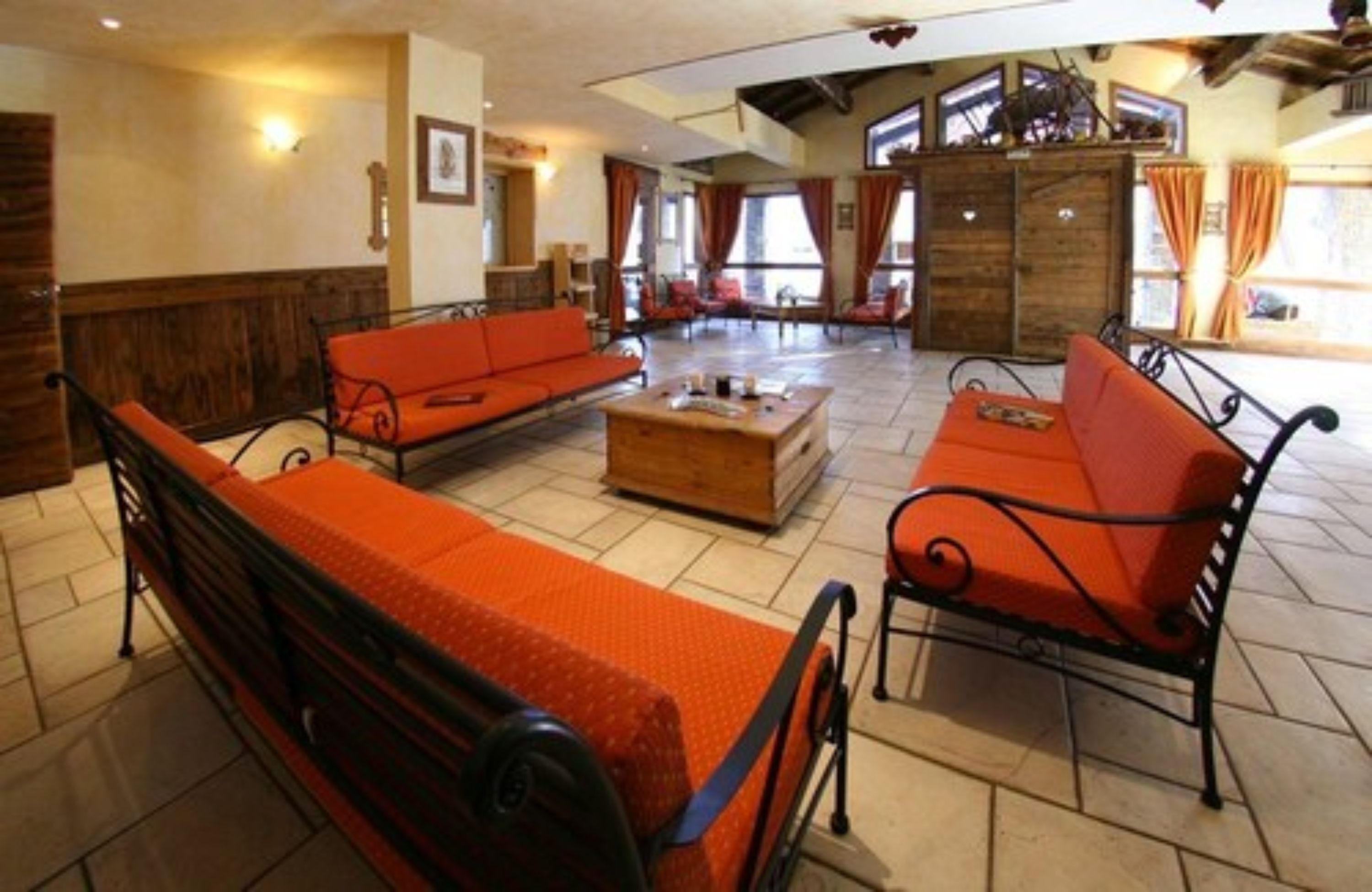 A spacious lobby with a high ceiling, a wooden reception desk, and a large window offering a view of the outdoors.