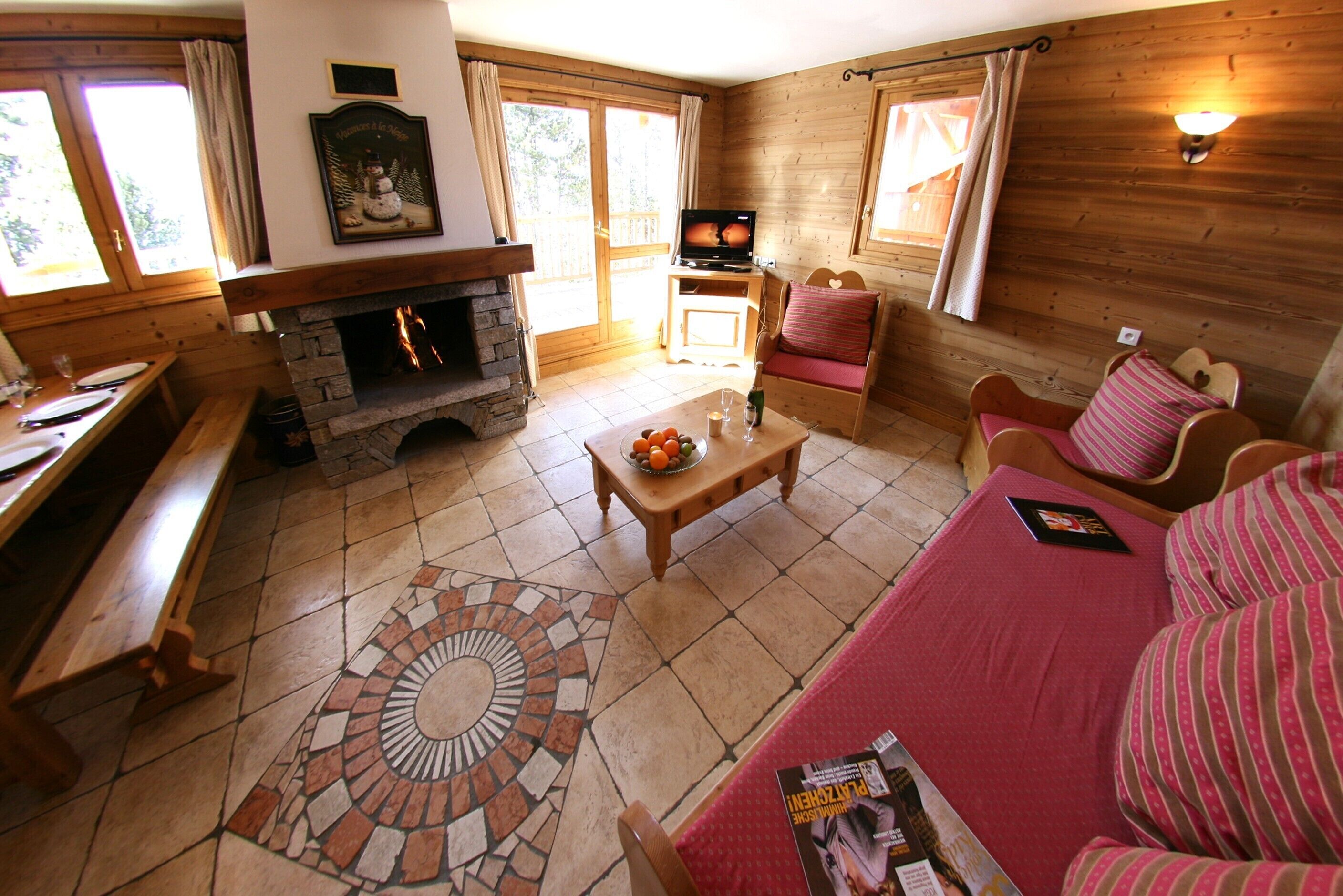 Un salon chaleureux avec une cheminée en pierre, des meubles en bois et un sol carrelé.