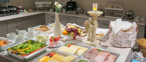 A buffet with various food items including salads, cheeses, meats, and fruits.