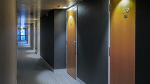 A hallway with dark walls and wooden doors, each marked with a number. - Hotel Kauppi (Tampere)