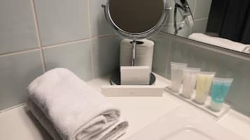 A bathroom with a white sink, a mirror, a towel, and a spa kit.