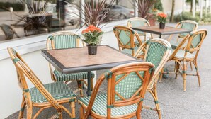 An outdoor seating area with wicker chairs and tables, potted plants, and a view of the street. - Hotel Kauppi (Tampere)