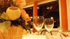 Una mesa de comedor dispuesta con copas de vino, un cesto de flores y cubiertos.