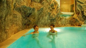 Una piscina interior con paredes rocosas y una superficie de agua azul cristalina.