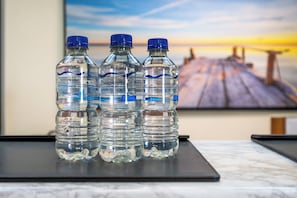 Three water bottles on a black surface with a blurred background of a wooden dock and a sunset.