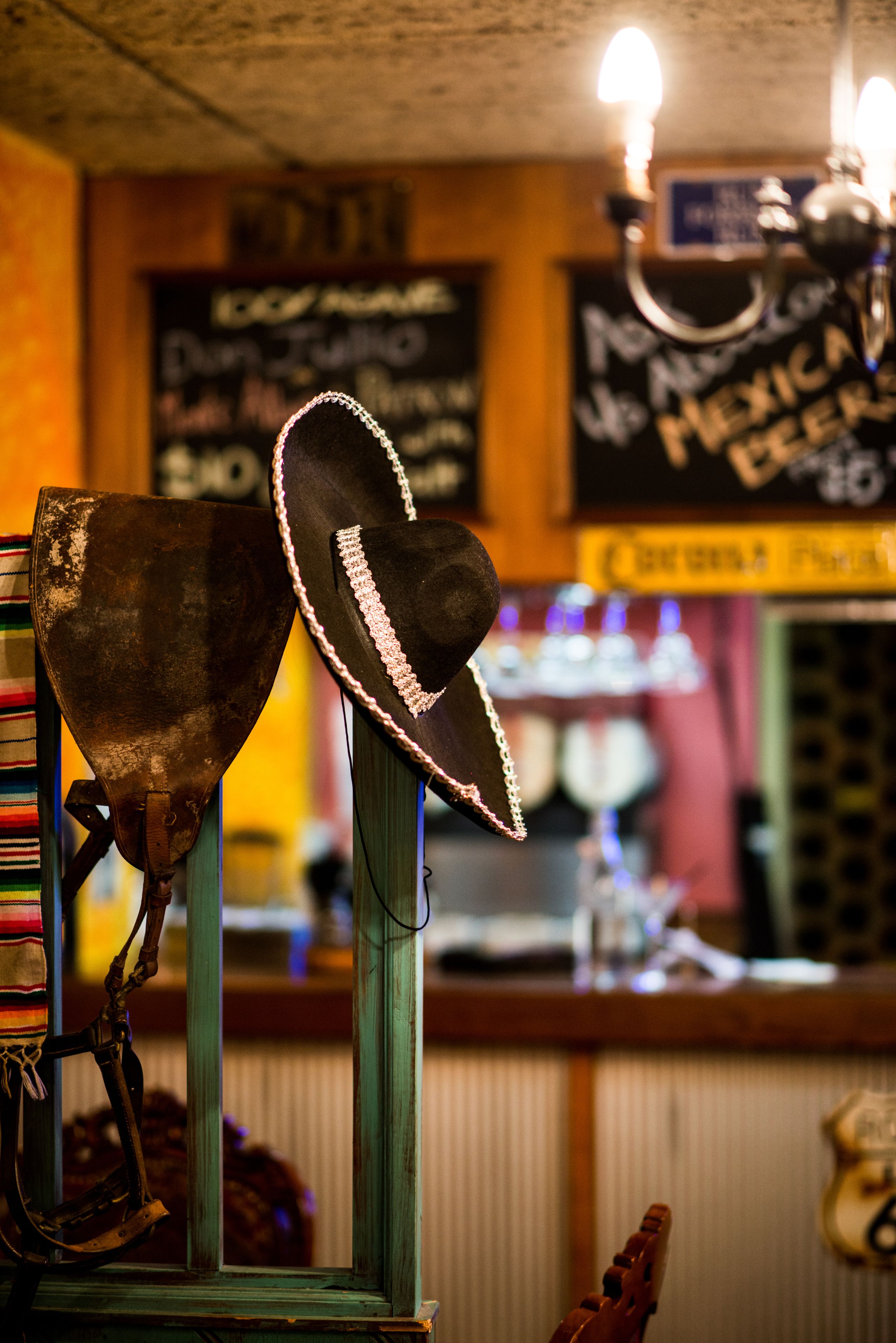 En bar med en rustik inredning, med en hatt på ett stativ och en gammal jukebox i bakgrunden.