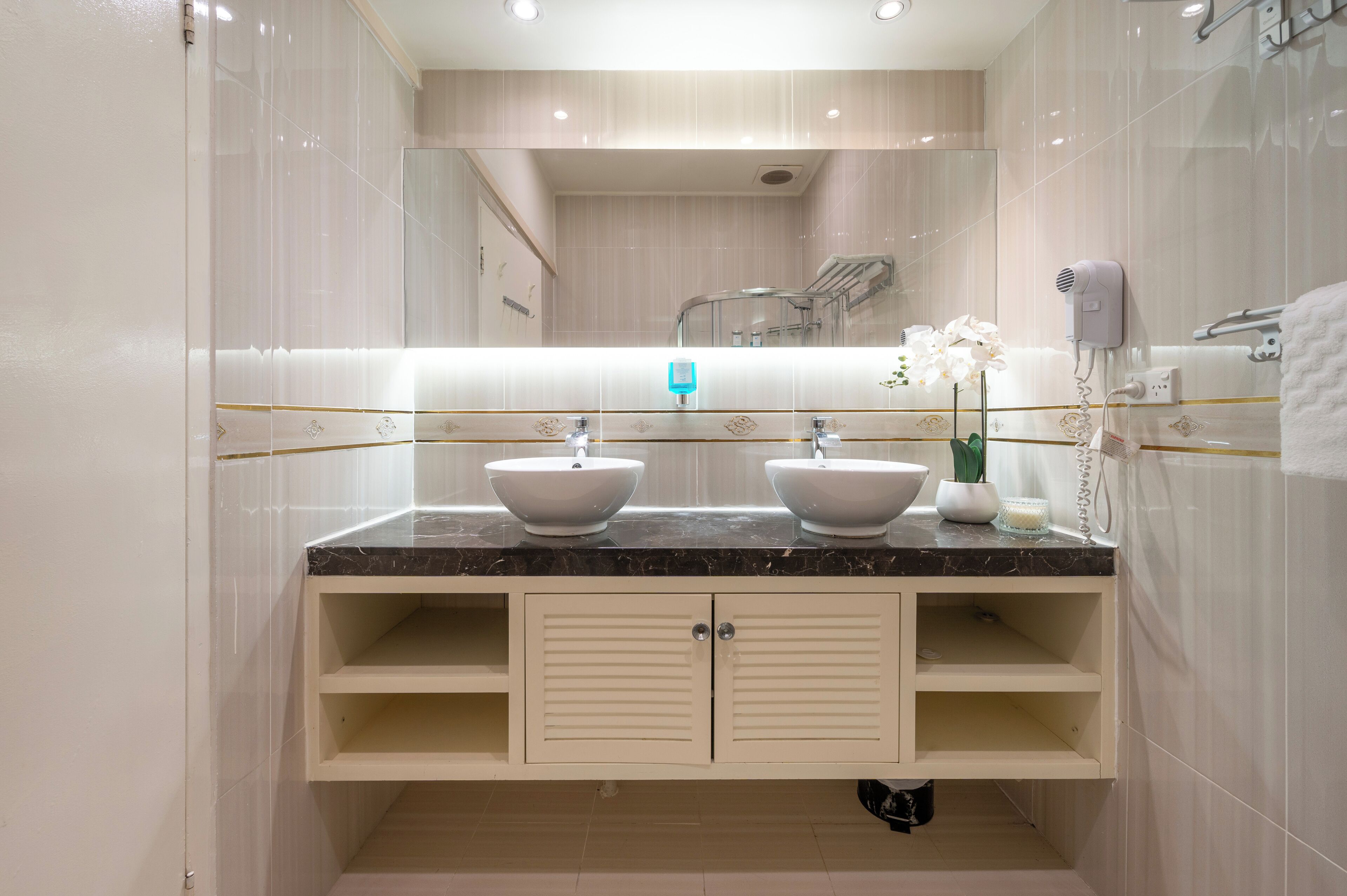 A modern bathroom with two sinks, a large mirror, and a hairdryer on the wall.
