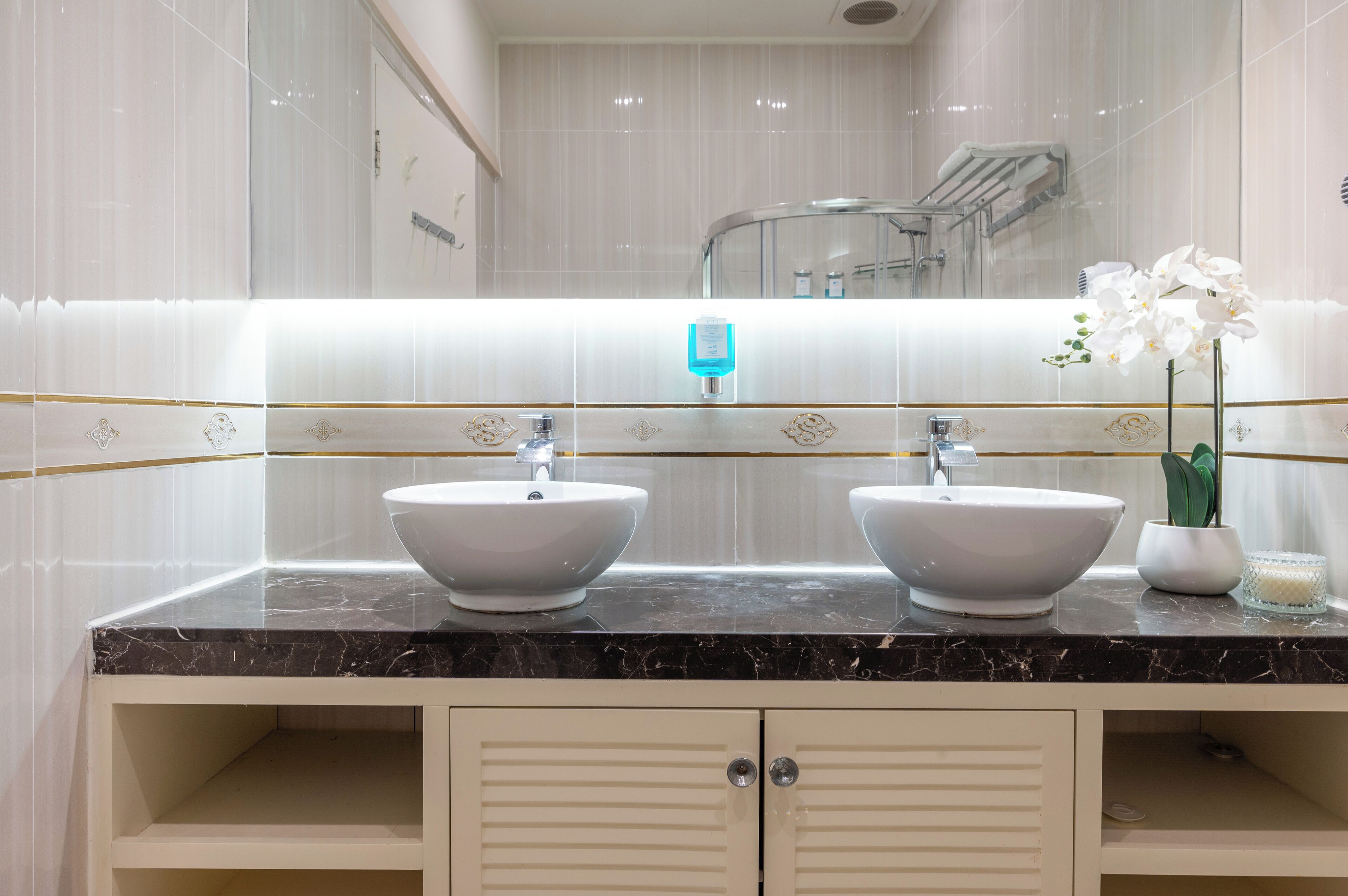A bathroom with two sinks, a mirror, and a shower.