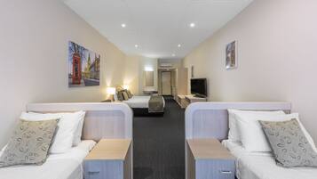 Ein Hotelzimmer mit zwei Betten, einem Fernseher, einem Schreibtisch und einem Bild an der Wand.