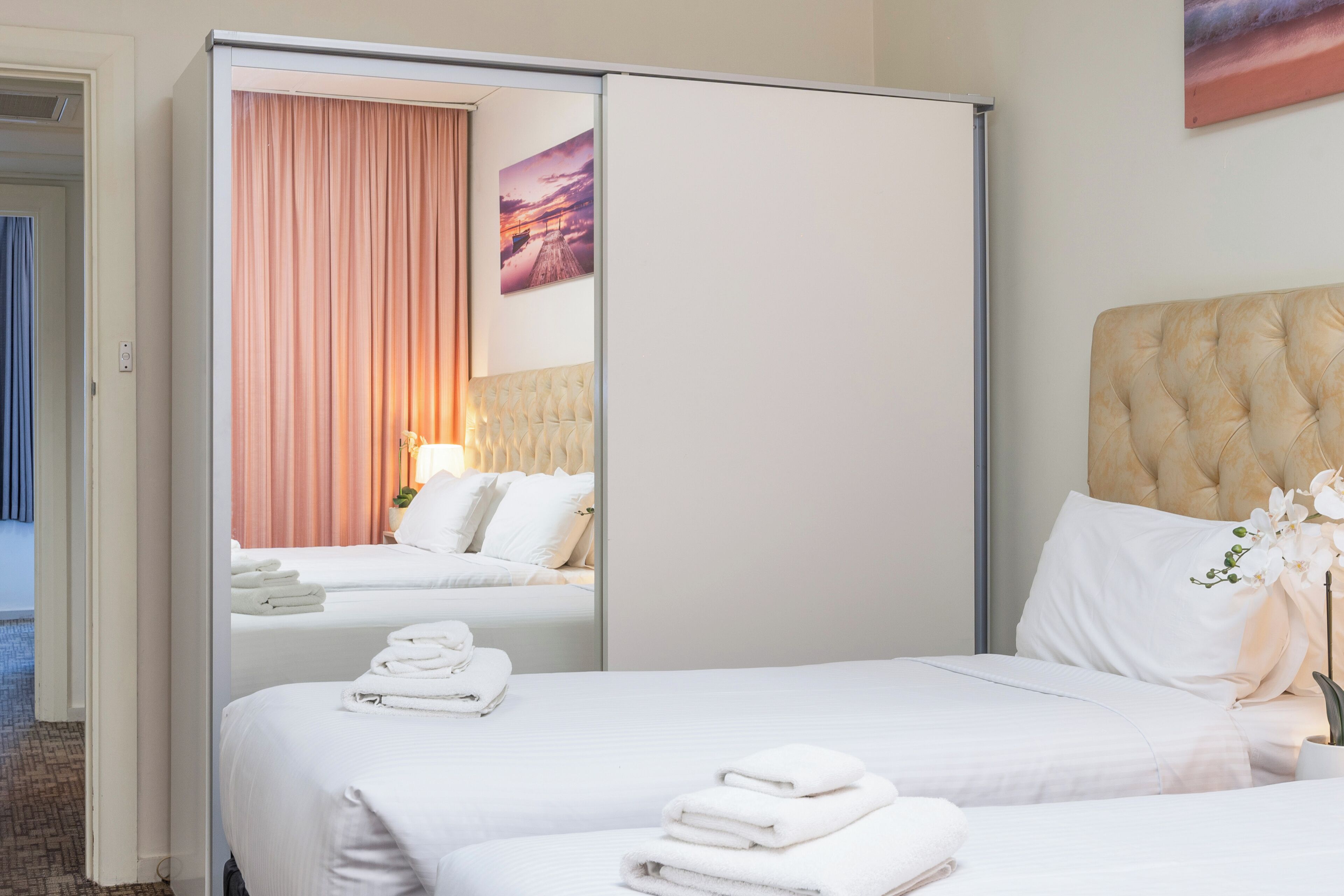 A hotel room with a bed, a wardrobe, and a painting on the wall.