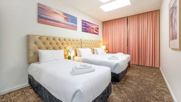 A hotel room with two beds, a large tufted headboard, and a view of the city.