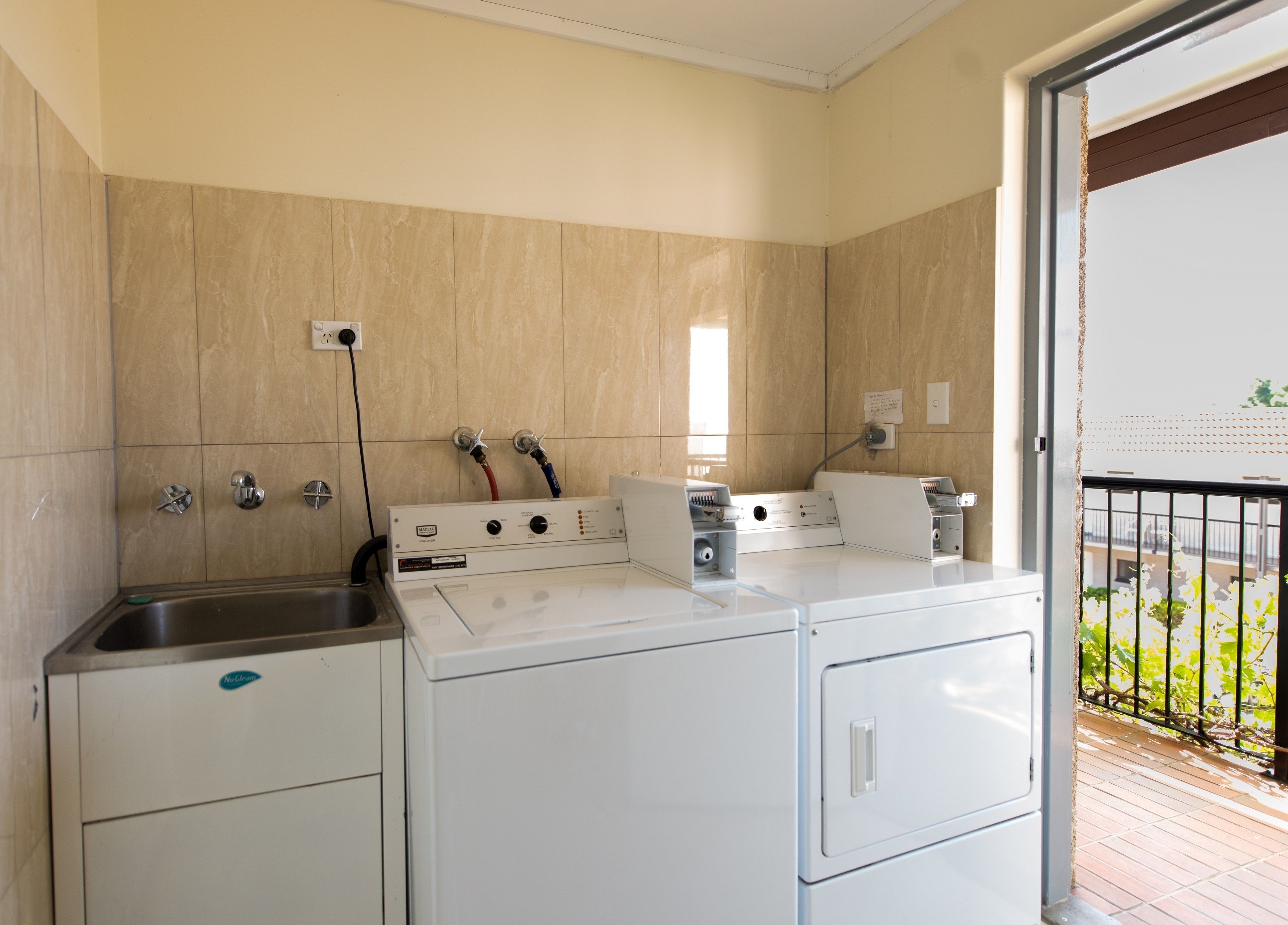 A compact kitchen with a built-in washer and dryer, a sink, and a window providing natural light.