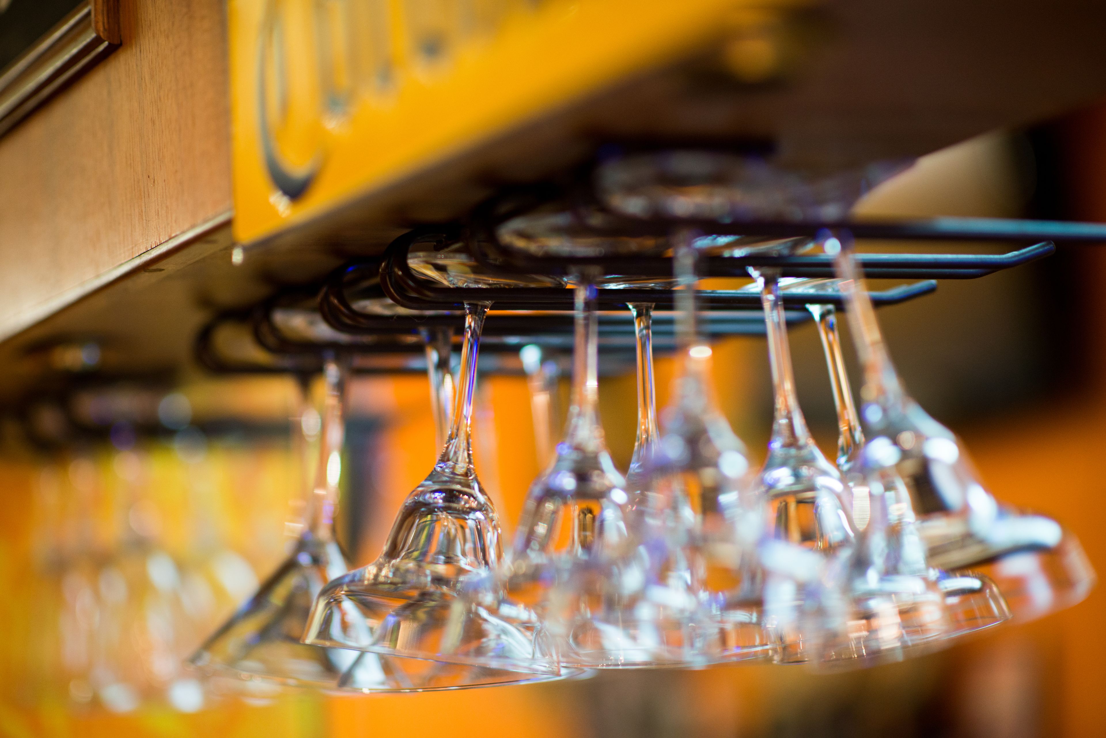 A row of clear wine glasses hanging from a rack.