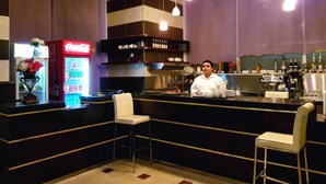 A bar area with a Coca-Cola refrigerator, a coffee machine, and bar stools. - Al Muhanna Plaza Hotel (Salmiya)