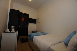 A small, clean room with a bed, a desk, and a television mounted on the wall.