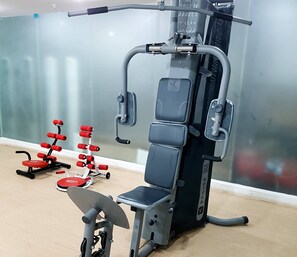 Une salle de sport équipée d’un banc de développé couché, d’une machine à presses à cuisses et d’une machine à câbles.