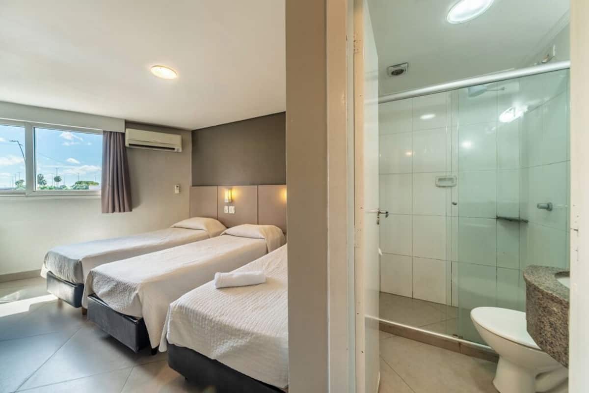 Habitación de hotel con dos camas, ducha y retrete.
