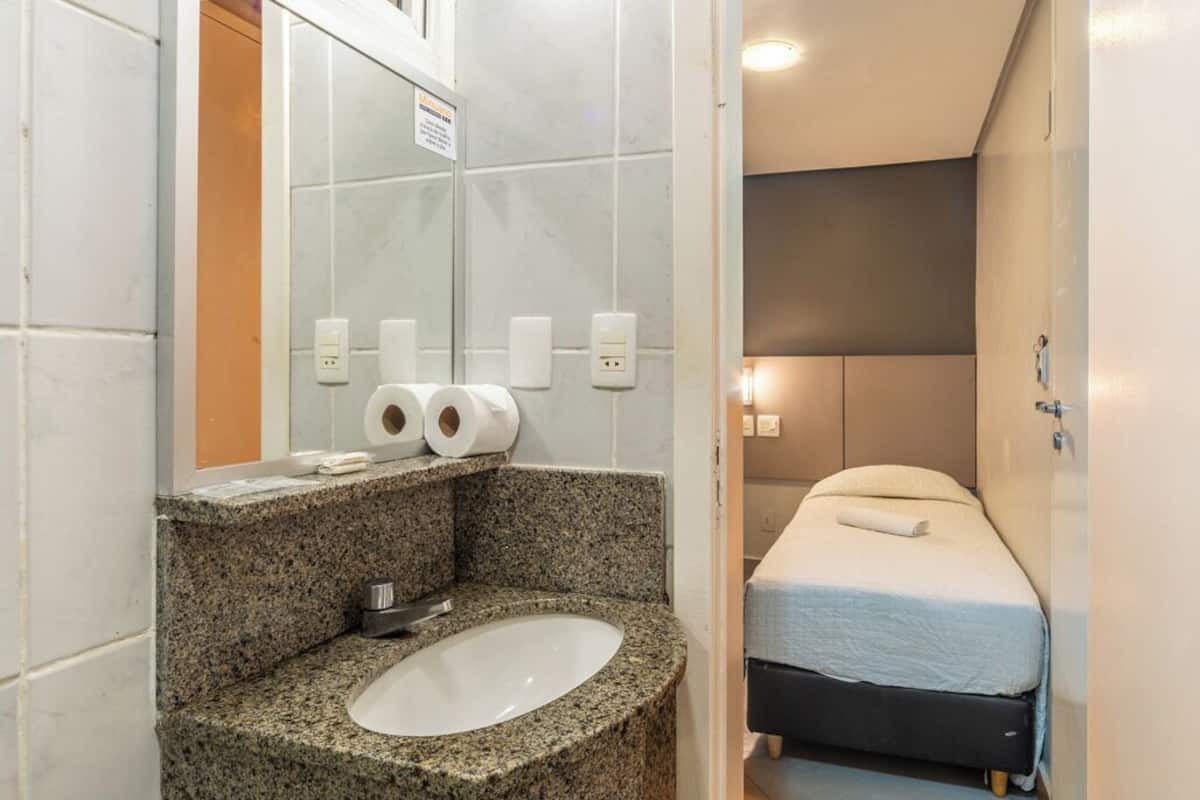 Un baño con lavamanos de granito, dos rollos de papel higiénico y un espejo.