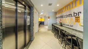 A hotel corridor with a bar area, elevator, and a sign for www.minhotel.com.br. - Hotel Minuano Express (Porto Alegre)