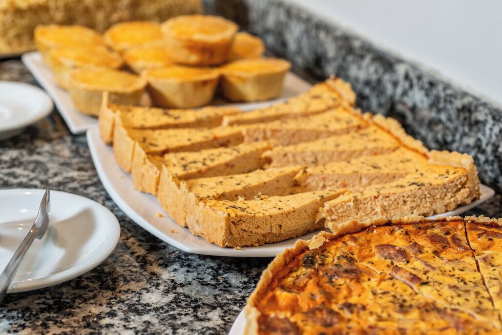A buffet with various food items including quiches and a large pie.